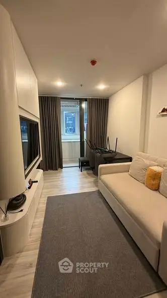 Modern living room with cozy sofa and large TV, featuring sleek design and ample natural light.