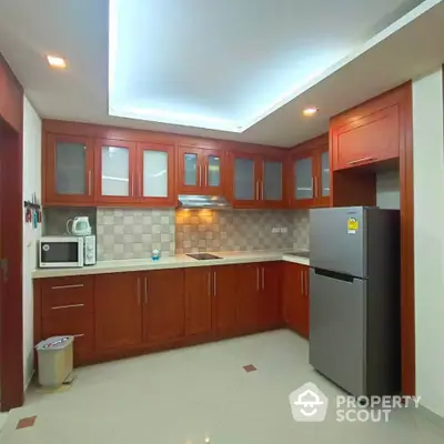 Spacious kitchen with modern wooden cabinets and stainless steel appliances