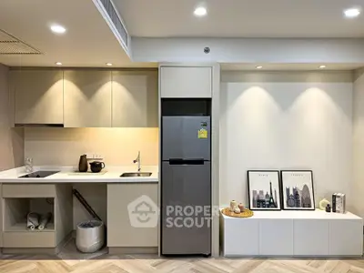 Modern kitchen with sleek cabinetry and stainless steel fridge in stylish apartment.
