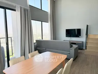 Modern living room with high ceilings, large windows, and city view in a stylish apartment.