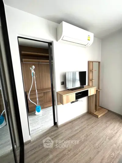 Modern bedroom with built-in wardrobe and air conditioning, featuring sleek wooden flooring and minimalist design.