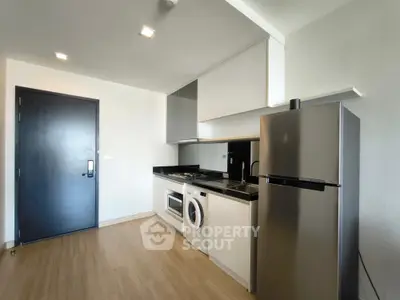 Modern kitchen with sleek appliances and wooden flooring in a stylish apartment.