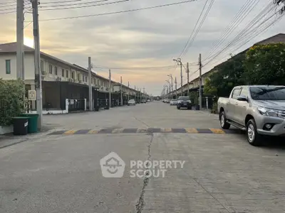 Charming suburban street view with modern townhouses and parked cars at sunset.