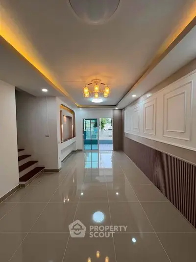 Elegant modern living room with stylish lighting and glossy tiled flooring, leading to a balcony with a view.