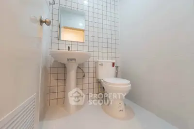 Modern minimalist bathroom with white tiles and sleek fixtures.