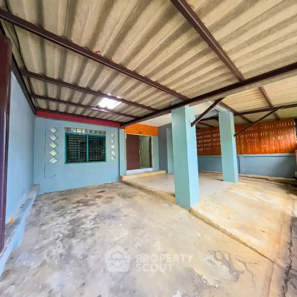 Spacious covered parking area with sturdy metal roof and concrete flooring, ideal for multiple vehicles.