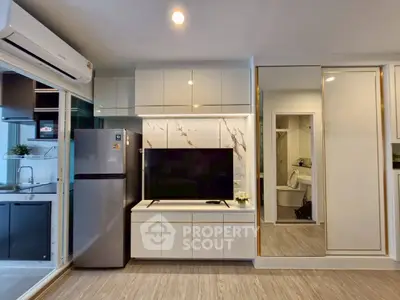 Modern living room with sleek design, featuring built-in cabinets, TV, and kitchen view.