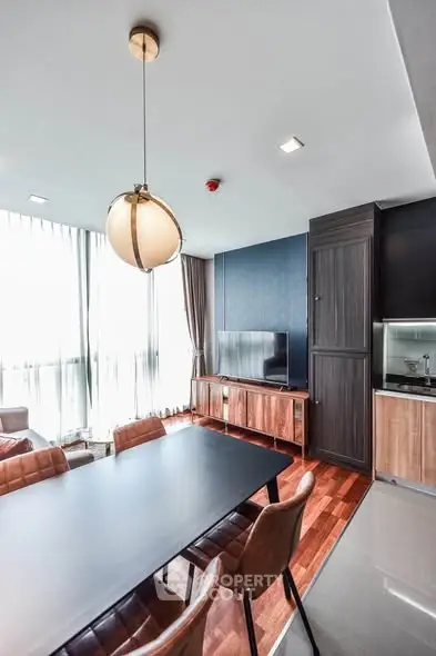 Modern dining area with stylish lighting and sleek wooden cabinetry in a bright apartment.