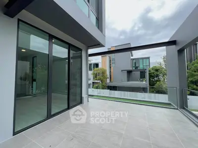 Modern balcony with sleek glass railing and spacious tiled flooring in contemporary building.