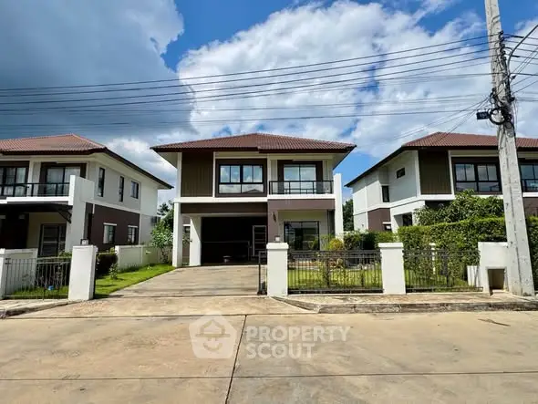 Modern two-story house with spacious driveway and lush greenery under a clear blue sky.