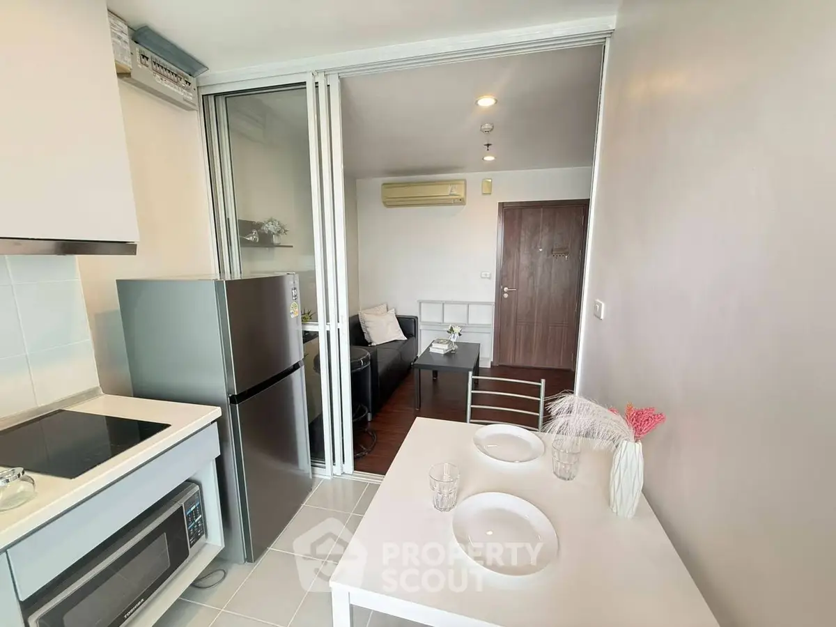 Modern compact kitchen and living area with sleek appliances and cozy dining setup.