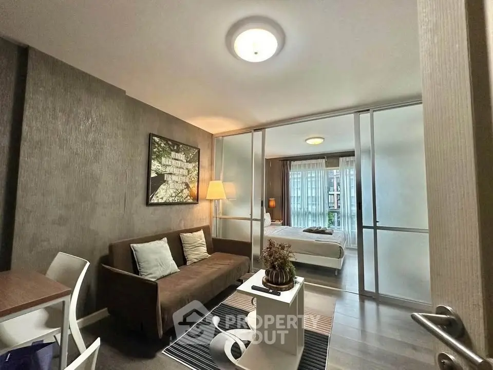 Modern living room with cozy sofa and stylish decor leading to a bright bedroom.