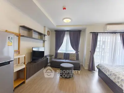 Modern studio apartment with open layout, featuring a cozy living area and natural light from large windows.