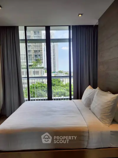 Modern bedroom with large window offering stunning city view in luxury apartment.