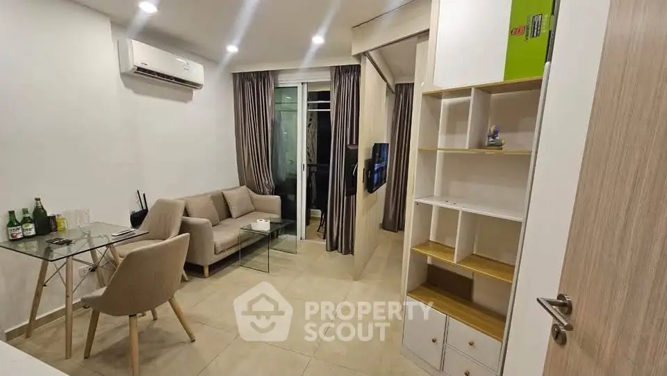 Modern living room with cozy sofa, glass table, and stylish shelving in a well-lit apartment.