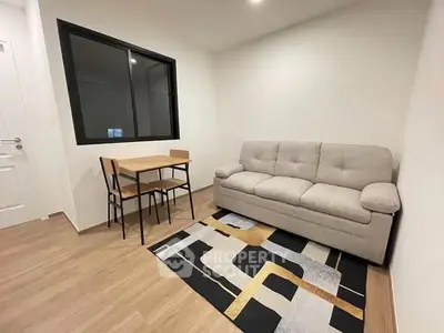 Cozy living room with modern sofa and dining table, featuring stylish decor and wooden flooring.