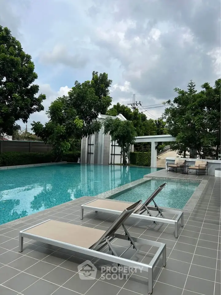 Luxurious outdoor pool area with modern lounge chairs and lush greenery, perfect for relaxation and leisure.