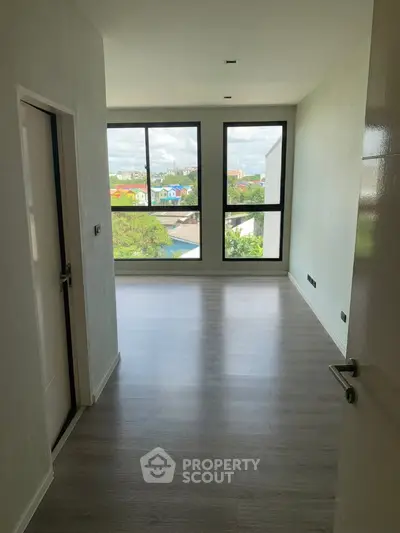 Bright empty room with large windows and modern flooring, offering a potential for customization.