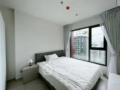 Modern bedroom with large window offering city view in high-rise apartment.