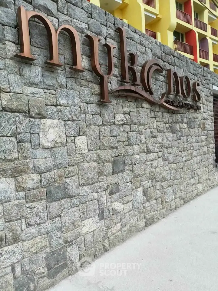 Elegant stone facade of Mykonos condominium with stylish signage.