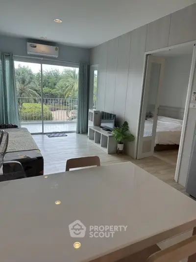 Modern open-plan living room with balcony and bedroom view