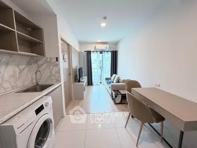 Modern open-plan living room with kitchen, featuring sleek design and natural light.