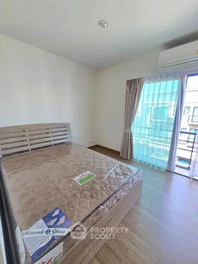 Bright bedroom with wooden flooring and large window access to balcony