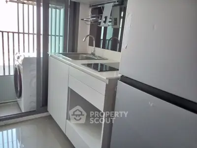 Modern kitchen with sleek appliances and washing machine in compact layout.