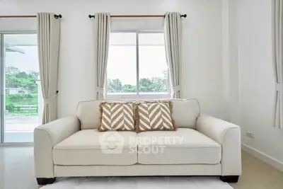 Bright living room with elegant sofa and large windows offering scenic views.