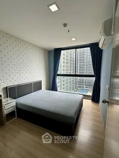 Modern bedroom with large window offering city view in high-rise apartment