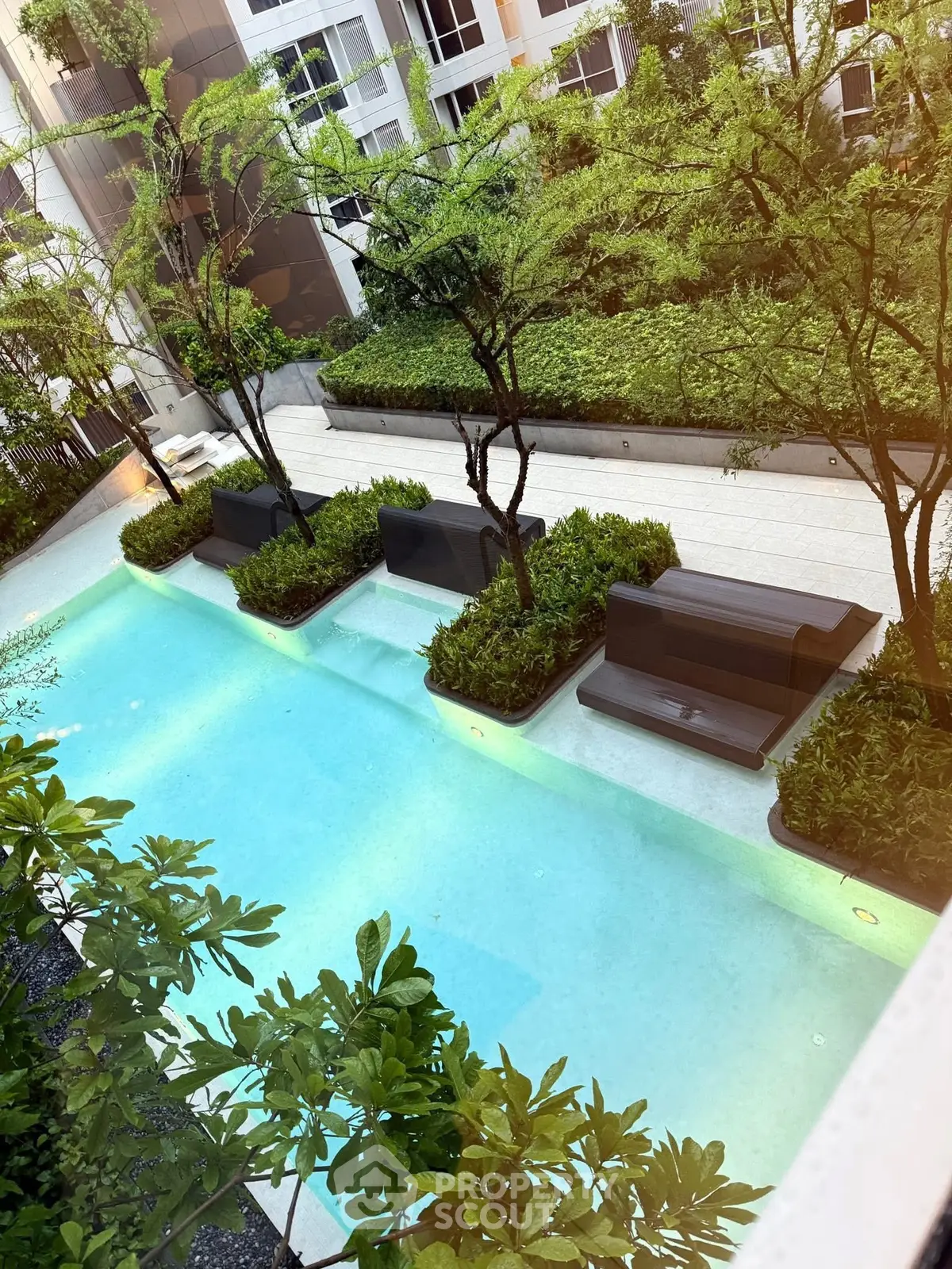 Luxurious residential pool area with lush greenery and modern seating.
