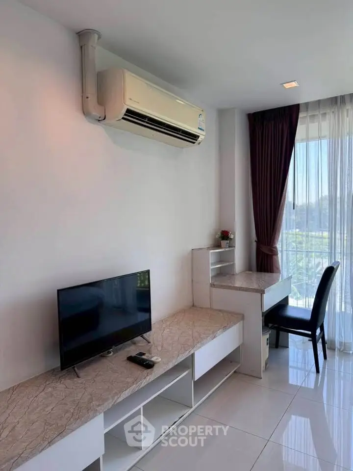 Modern living room with air conditioning and natural light, featuring a sleek TV setup and elegant curtains.