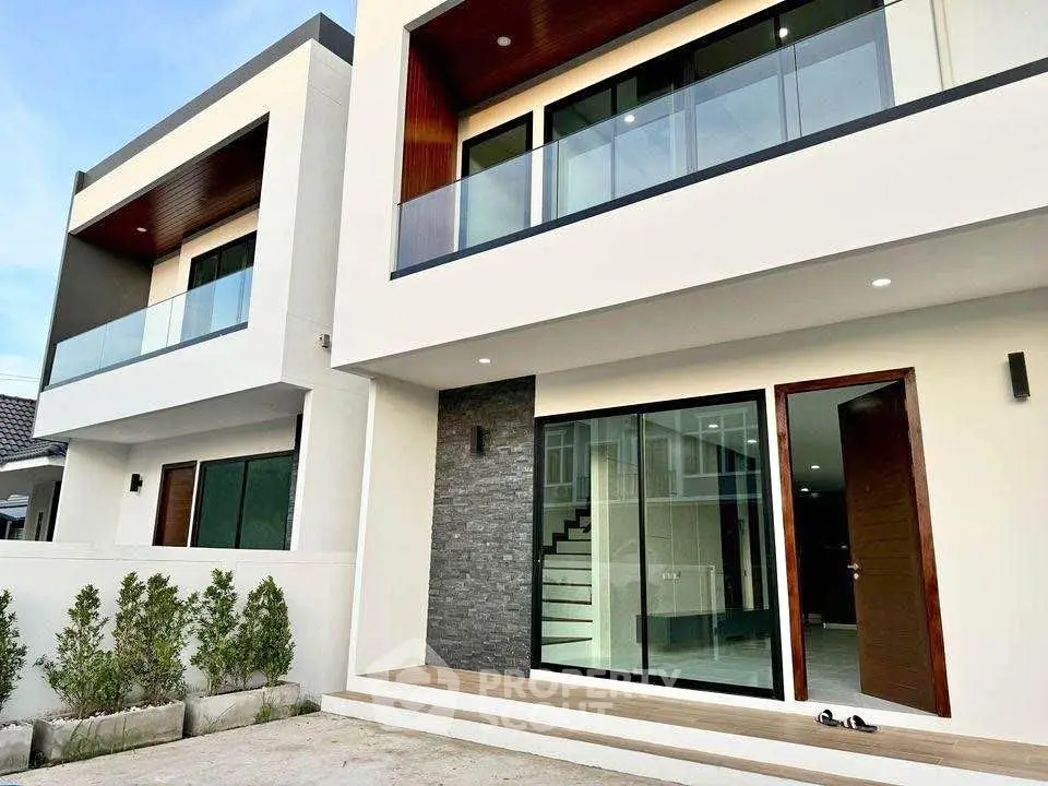 Modern two-story house with sleek design and large glass windows.