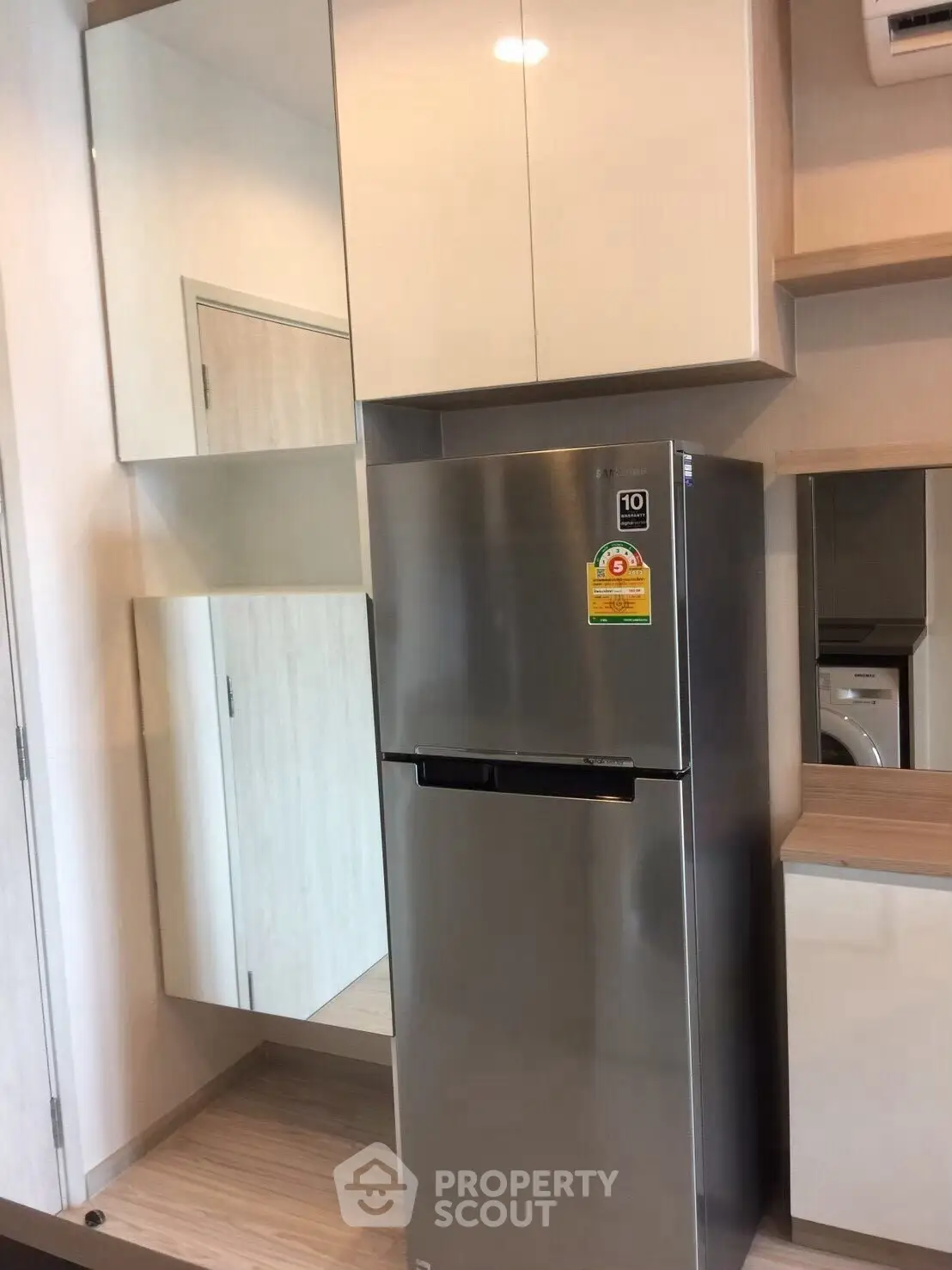 Modern kitchen with sleek stainless steel fridge and mirrored cabinets.