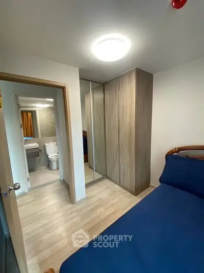 Cozy bedroom with mirrored wardrobe and ensuite bathroom in modern apartment.