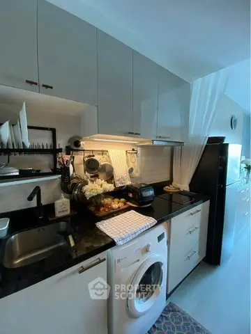Modern kitchen with sleek cabinets, washing machine, and stylish decor in a compact layout.