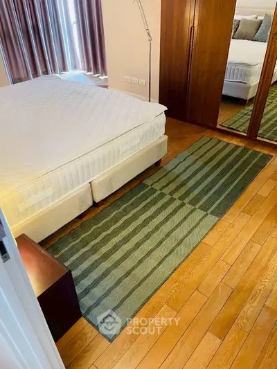 Cozy bedroom with wooden flooring and mirrored wardrobe