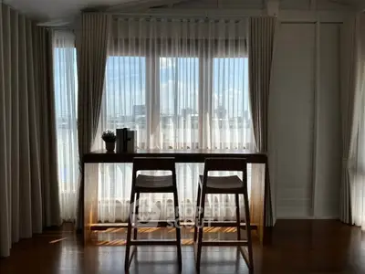 Bright and airy living room with large windows and elegant curtains, featuring a stylish wooden table and chairs.
