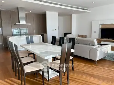 Spacious modern living and dining area with sleek furniture and open kitchen layout.