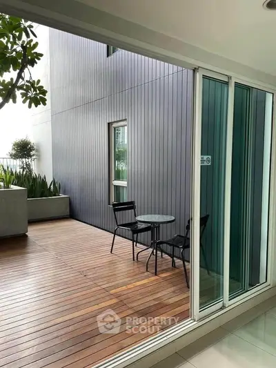 Modern balcony with wooden decking and stylish outdoor furniture in a contemporary building.