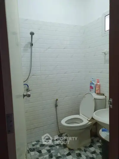 Compact bathroom with shower, toilet, and sink in tiled interior.