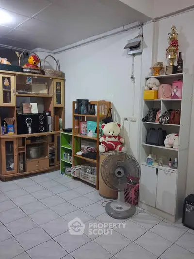Cozy living room with tiled floor, wooden shelves, and decorative items creating a warm atmosphere.