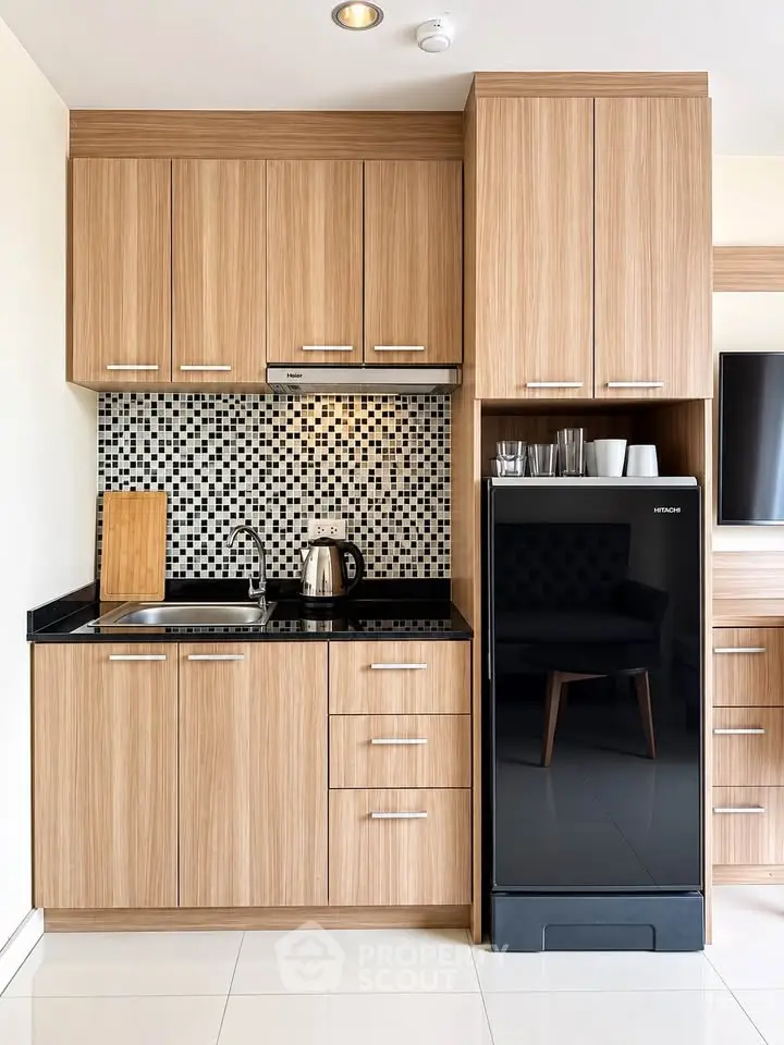 Modern kitchen with wooden cabinets and sleek black fridge in stylish apartment.