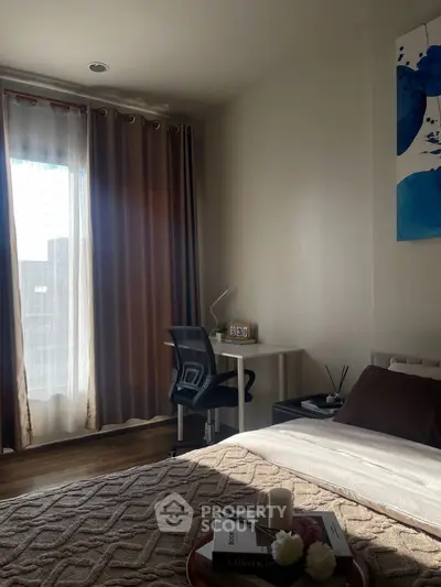 Cozy bedroom with natural light, modern decor, and a small study area.