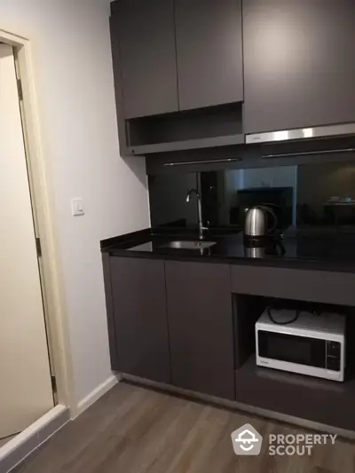 Modern compact kitchen with sleek black cabinets and appliances