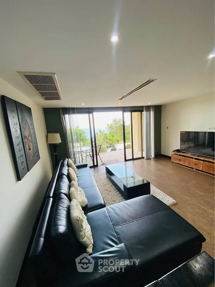 Spacious living room with modern decor and large windows offering a stunning view, perfect for relaxation.