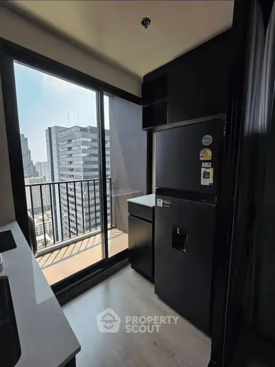 Modern kitchen with city view and sleek black appliances in high-rise apartment
