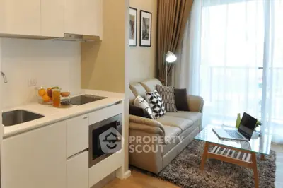 Modern living room with cozy sofa, stylish decor, and compact kitchen area.