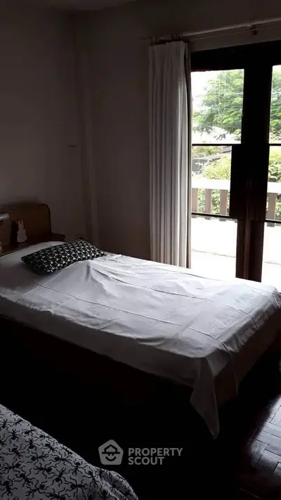 Cozy bedroom with single bed and balcony view, perfect for relaxation.