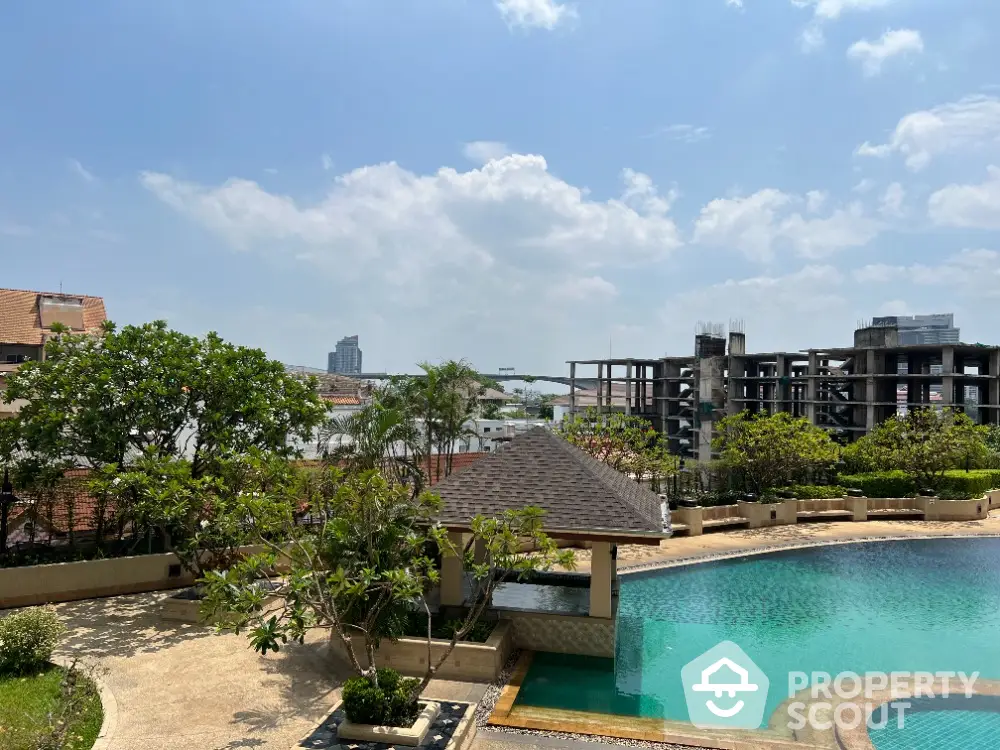 Luxurious residential pool area with lush greenery and clear blue sky, perfect for relaxation.